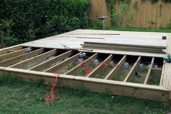Deck construction shows the deck with half covered decking and support beams underneath.