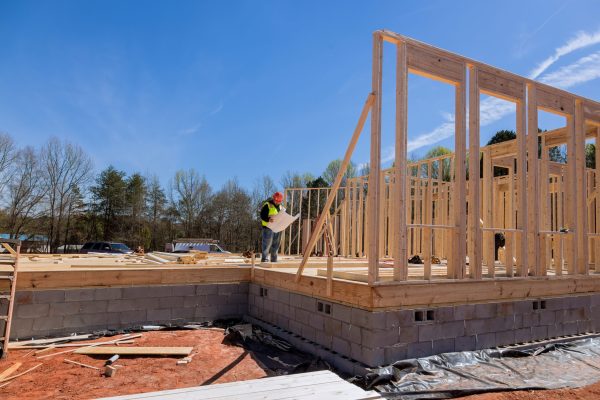 When construction project is underway safety inspector checks quality of work being performed on site using construction blueprint